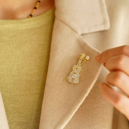 Delicate gold-tone violin brooch adorned with sparkling crystals and a small pearl for women music accessory