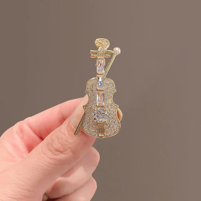 Gold-colored violin-shaped brooch adorned with clear crystals and a small pearl for women music accessories and clothing decoration