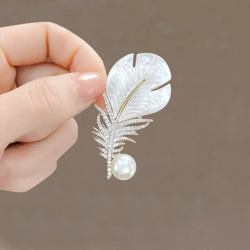 A delicate white mother-of-pearl feather brooch with rhinestones and a pearl for clothing decoration and music accessories