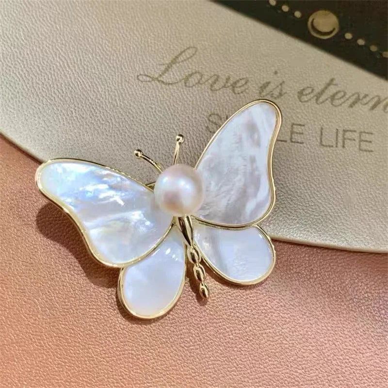 Elegant butterfly brooch with iridescent mother-of-pearl wings gold-tone frame and central pearl for clothing decoration