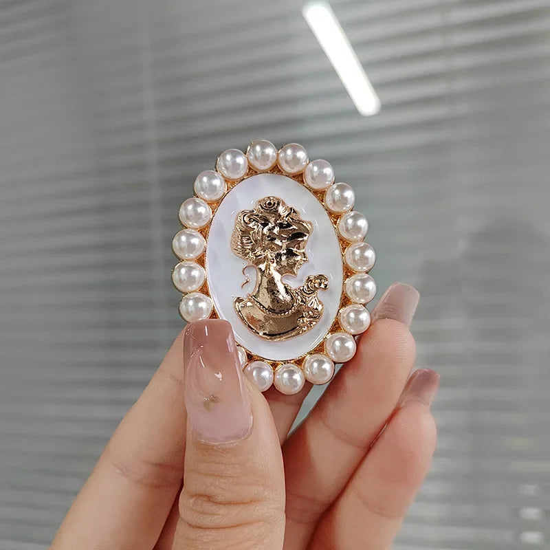 Delicate gold-toned cameo brooch with ornate profile design and pearl halo for exquisite music accessory decoration