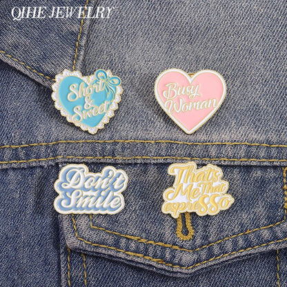 Set of four sweet enamel pins with heart and text designs in pastel colors and gold trim on denim fabric for clothes