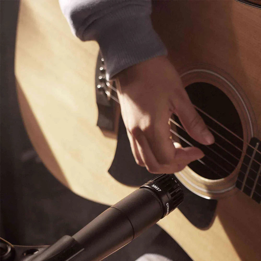 Black sm57 dynamic instrument microphone positioned near an acoustic guitar for beat music store recording