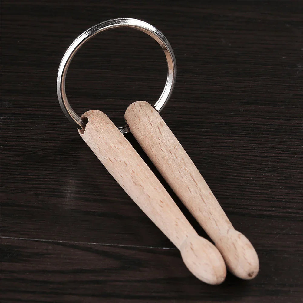 A pair of light wood drumsticks percussion attached to a silver metal percussion key ring keychain accessory