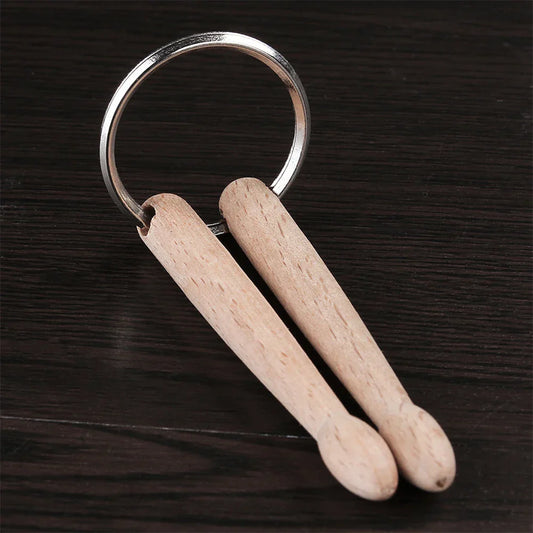 A pair of light wood drumsticks percussion attached to a silver metal percussion key ring keychain accessory