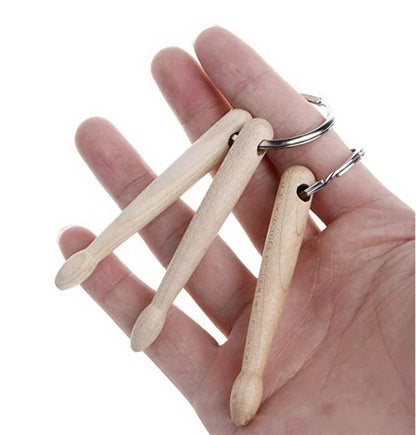 A set of three light-colored wooden drum sticks keychain for percussion use on a metal key ring fashion accessory