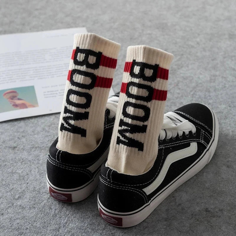 Cream-colored socks nice brand crew socks with male letter boom and red stripes worn with black vans sneakers