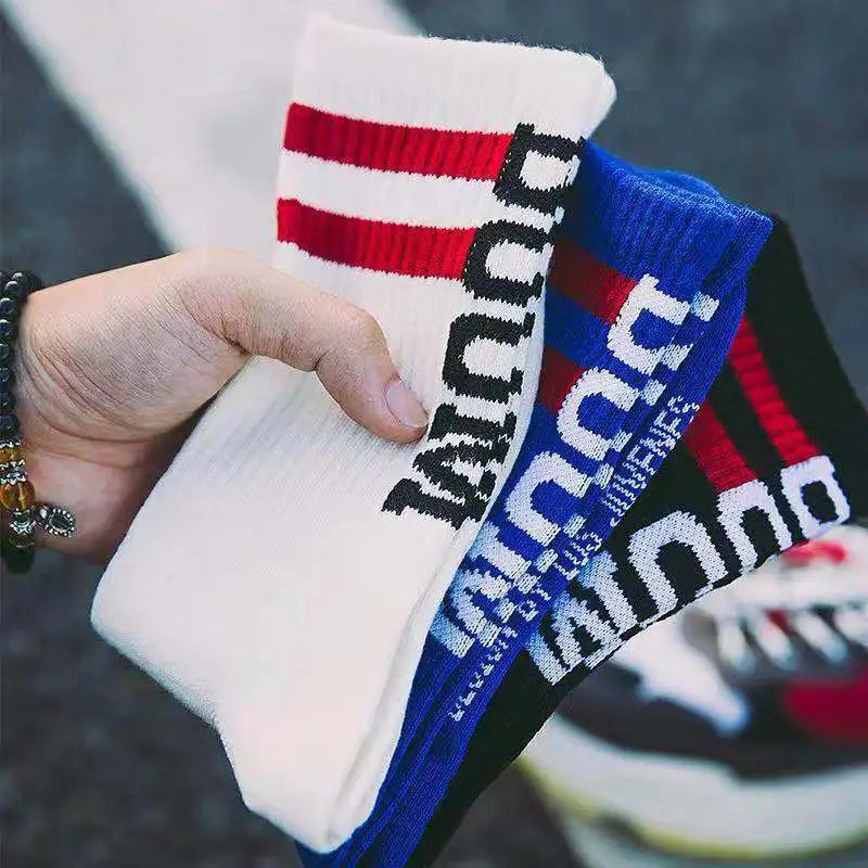 A hand holds colorful knitted socks nice brand featuring bold stripes and male letter boom for female tide european style