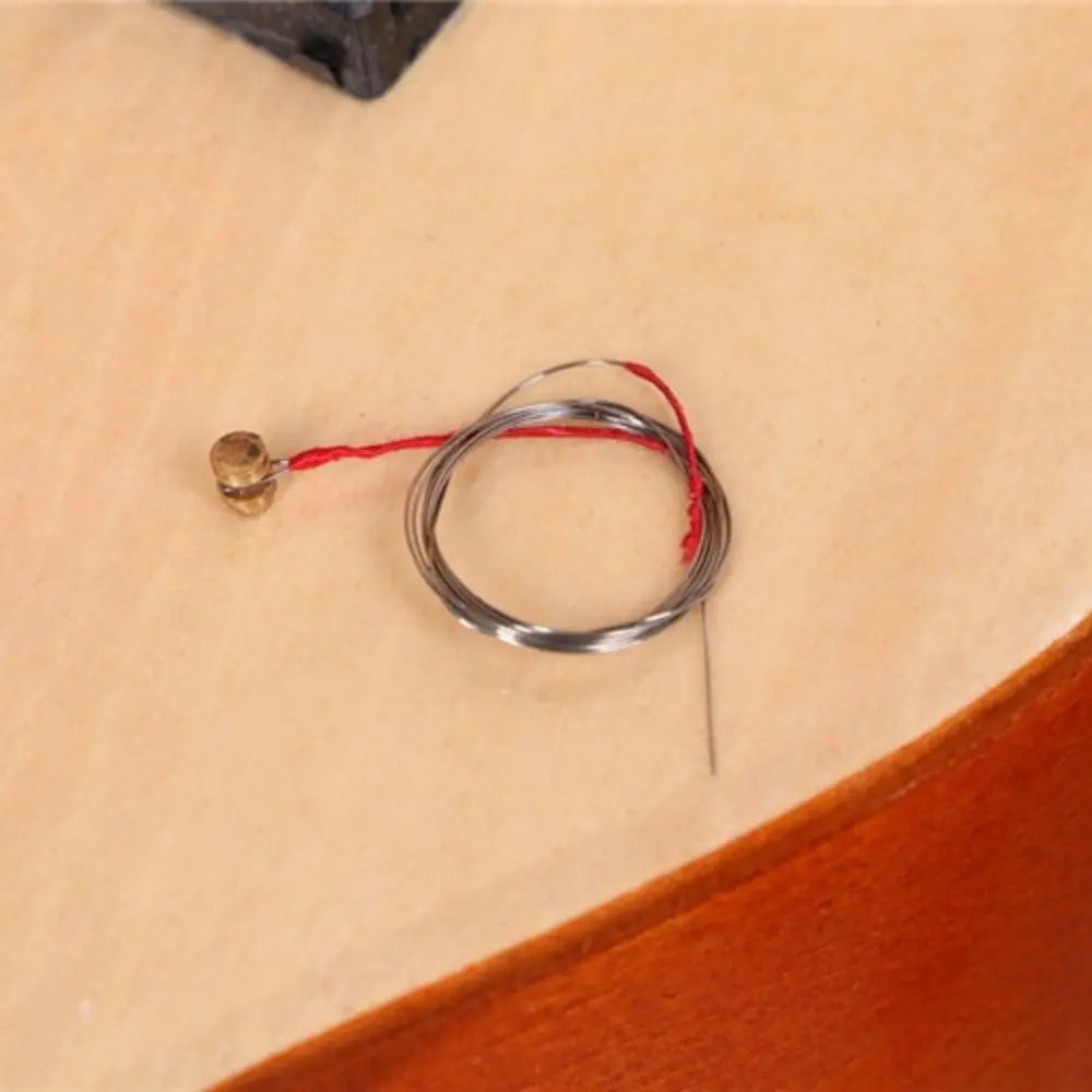 A coiled silver wire with red thread and brass connector for guitar classical adjustable string knob sound quality durable