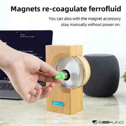 A sleek wooden base holds a transparent glass cylinder with black magnetic fluid responding to equipment motion sensor touch