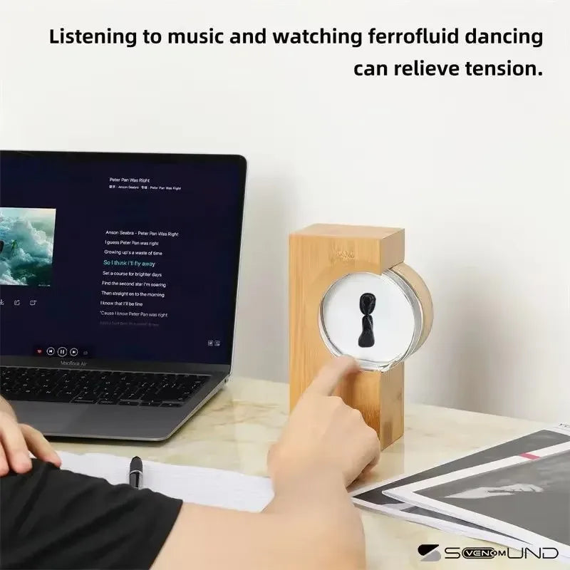 A sleek wooden-framed magnetic fluid art piece with a glass face responding to music sound touch and equipment motion sensor