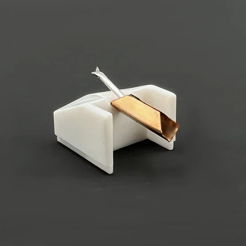 A sleek white plastic stylus rest holding a silver-tipped gold phonograph needle for essential DJ turntable use