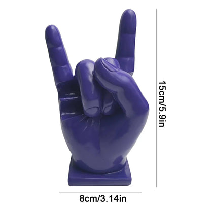 A glossy purple resin hand gesture sculpture on a square base serving as a drum stick holder and display stand