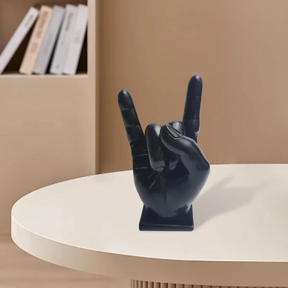 Black glossy resin hand sculpture making rock on sign serves as a modern drum stick holder and display stand for home decor