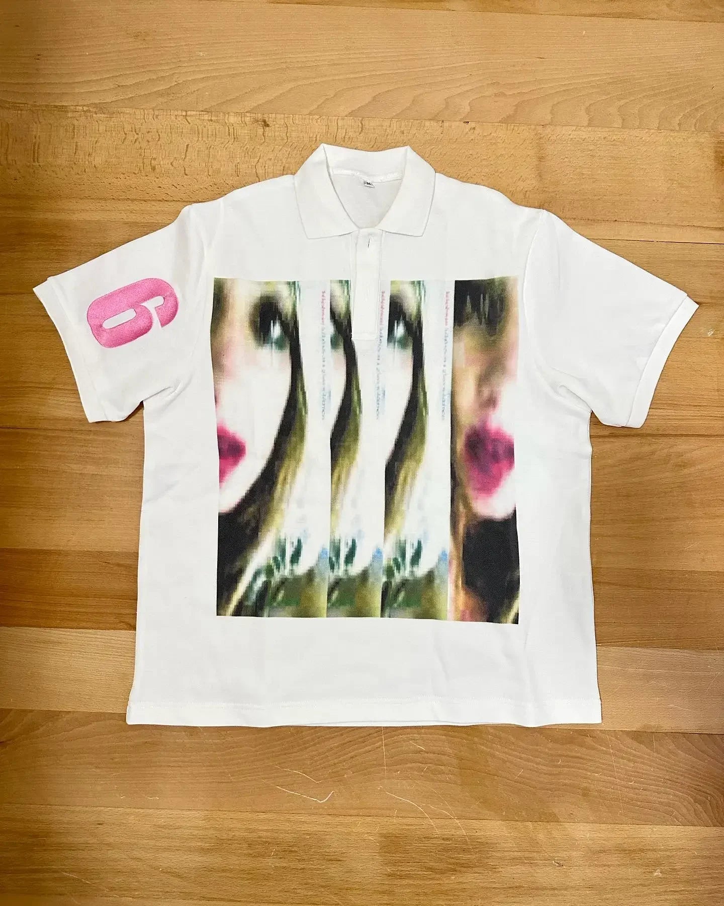 White short-sleeved streetwear shirt y2k featuring bold fragmented portrait print and bright pink logo on sleeve