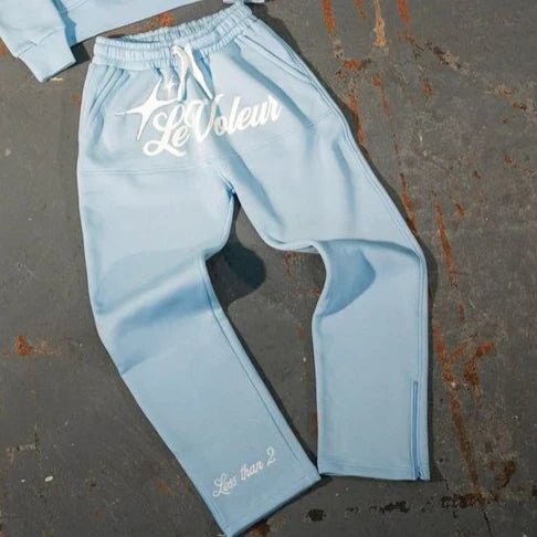 Light blue sweatpants with white embroidered le voleur logo and less than 2 text near cuff in y2k clothes mens piece set y2k
