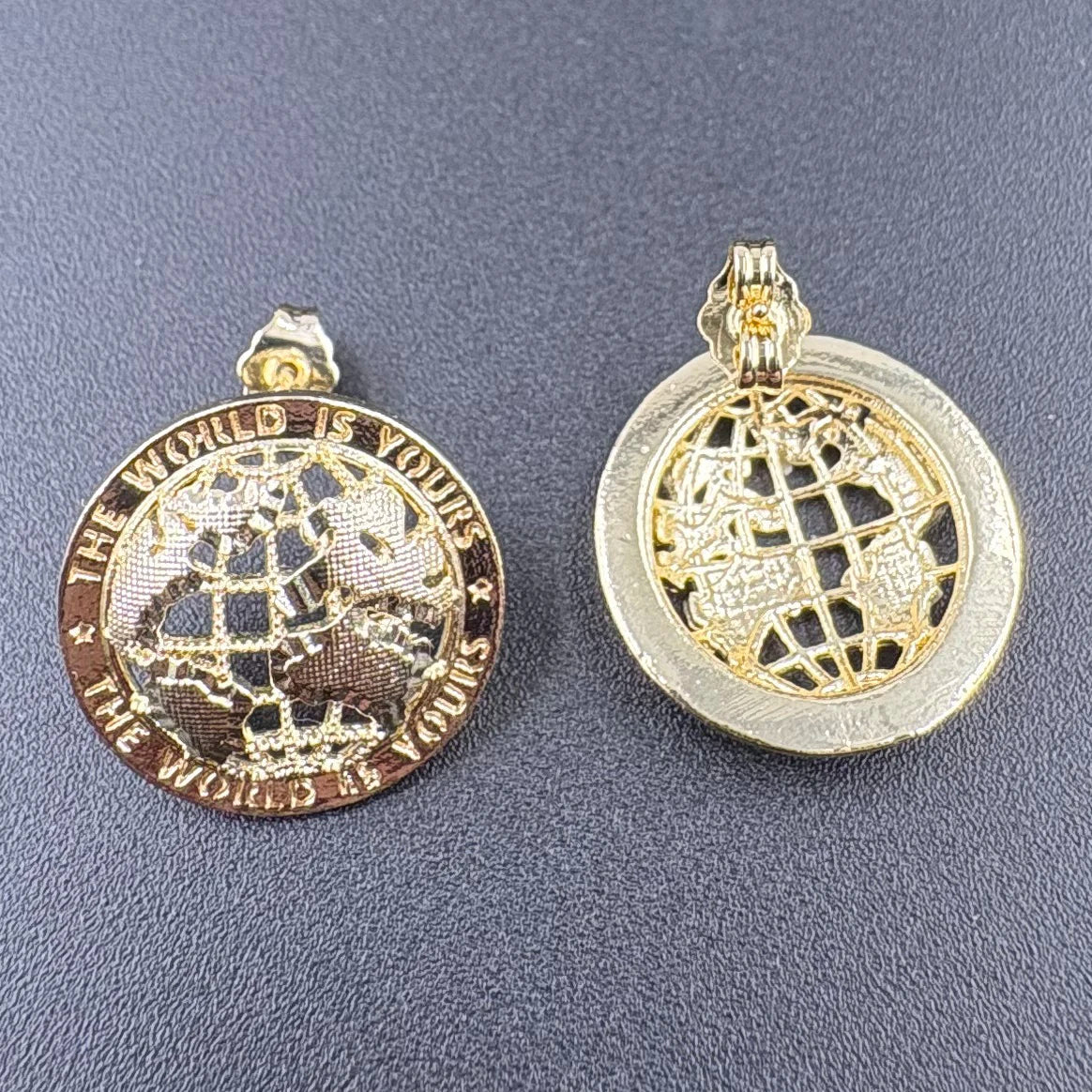 Two gold-toned hip hop stud earrings with globe charms and the inscription the world is yours, 14k gold plated