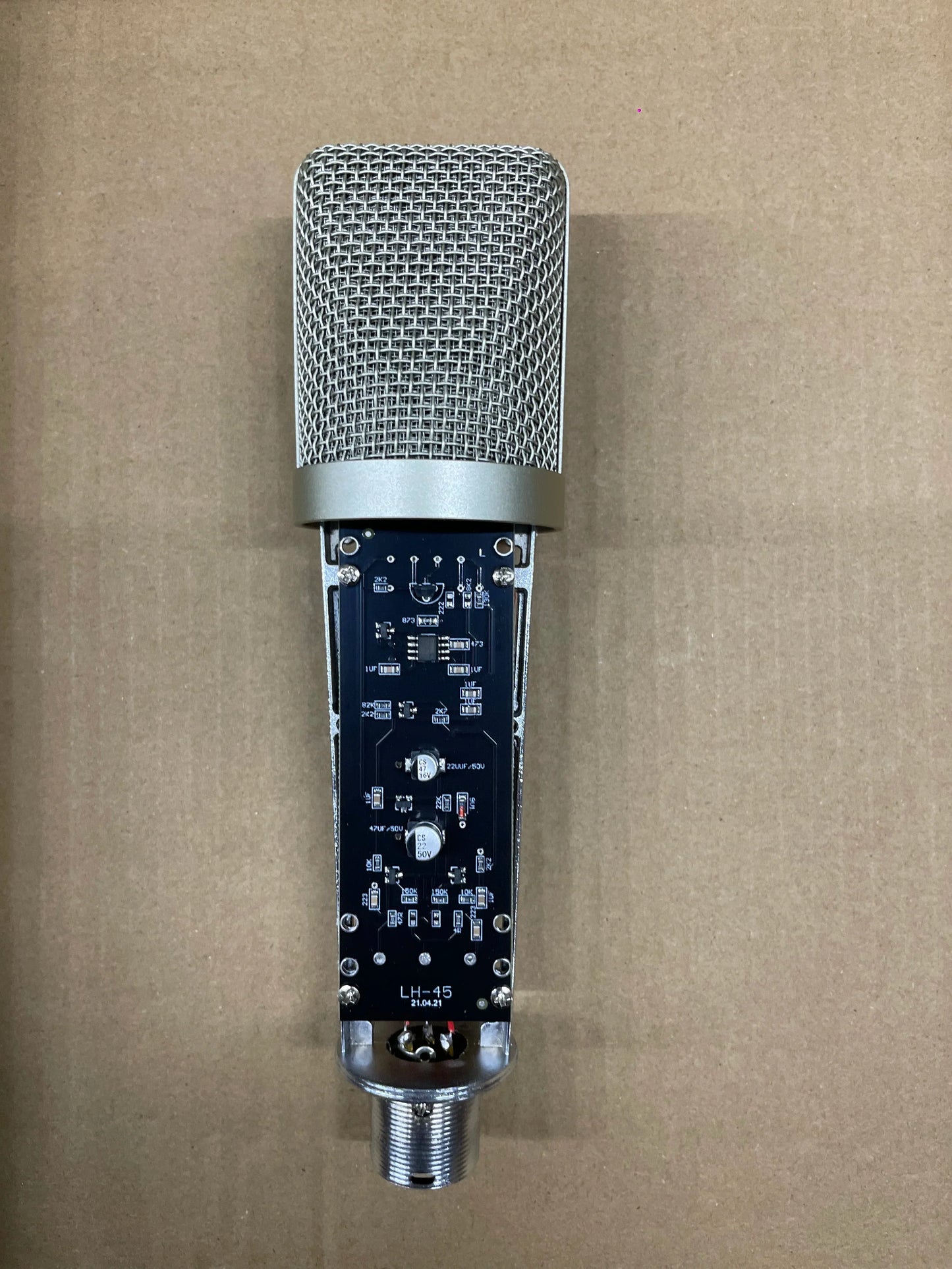 Silver mesh grille studio metal u87 condenser microphone with visible circuit board and xlr connector for recording podcasting voice