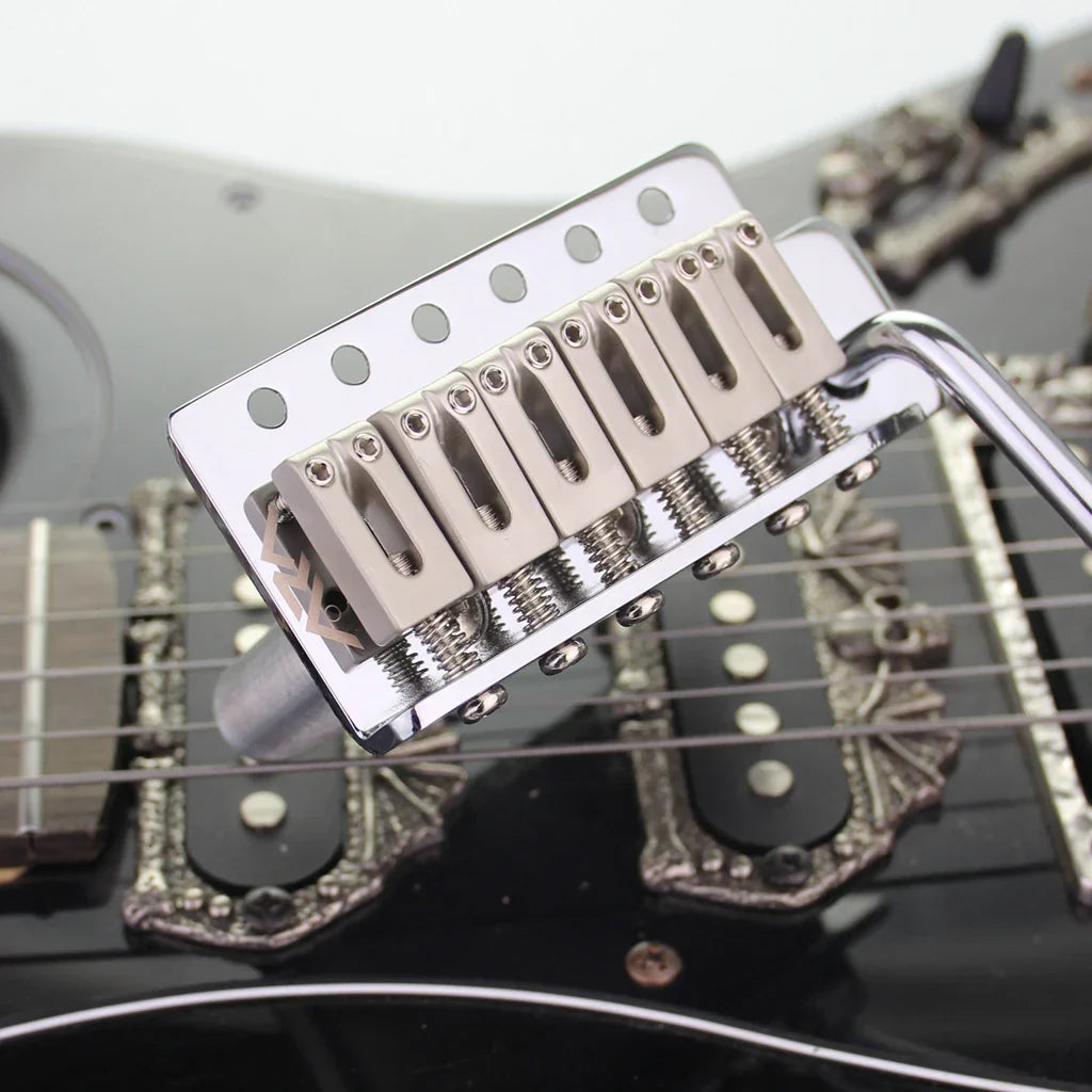 Shiny chrome tremolo bridge system with six saddles and base plate mounted on black stratocaster st electric guitar body