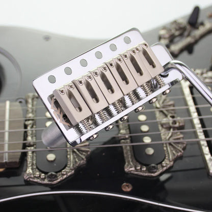 Shiny chrome tremolo bridge system with six saddles and base plate mounted on black stratocaster st electric guitar body