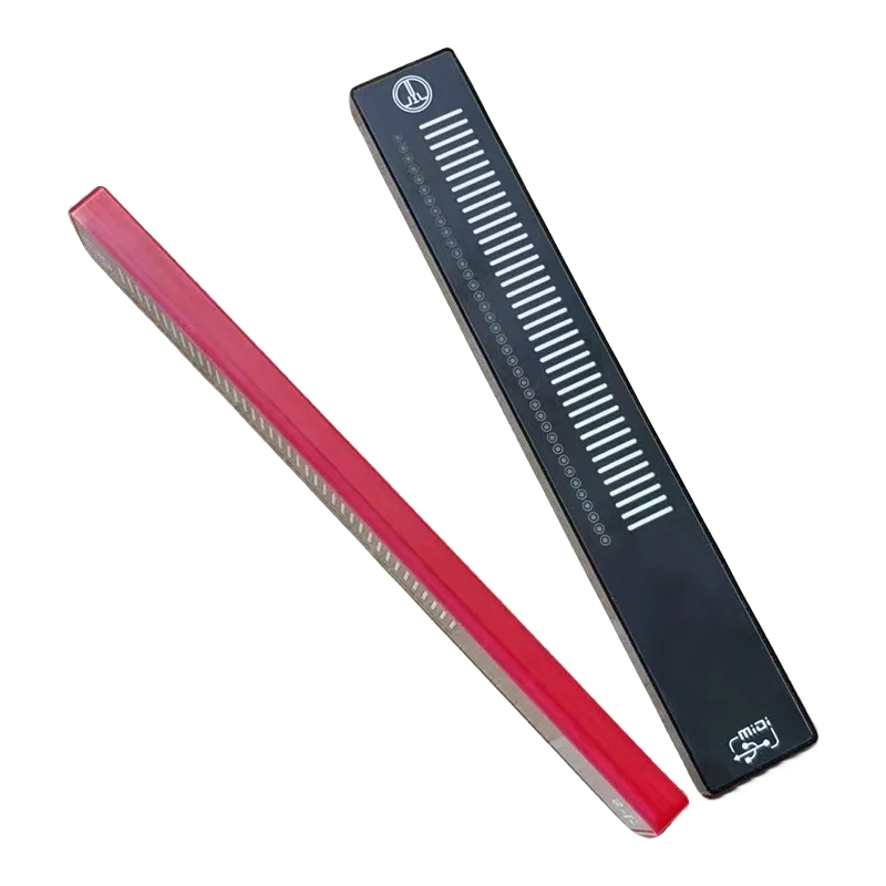 Red and black plastic comb with white teeth and measurement markings for sliding touch music controller volume anchors recording use