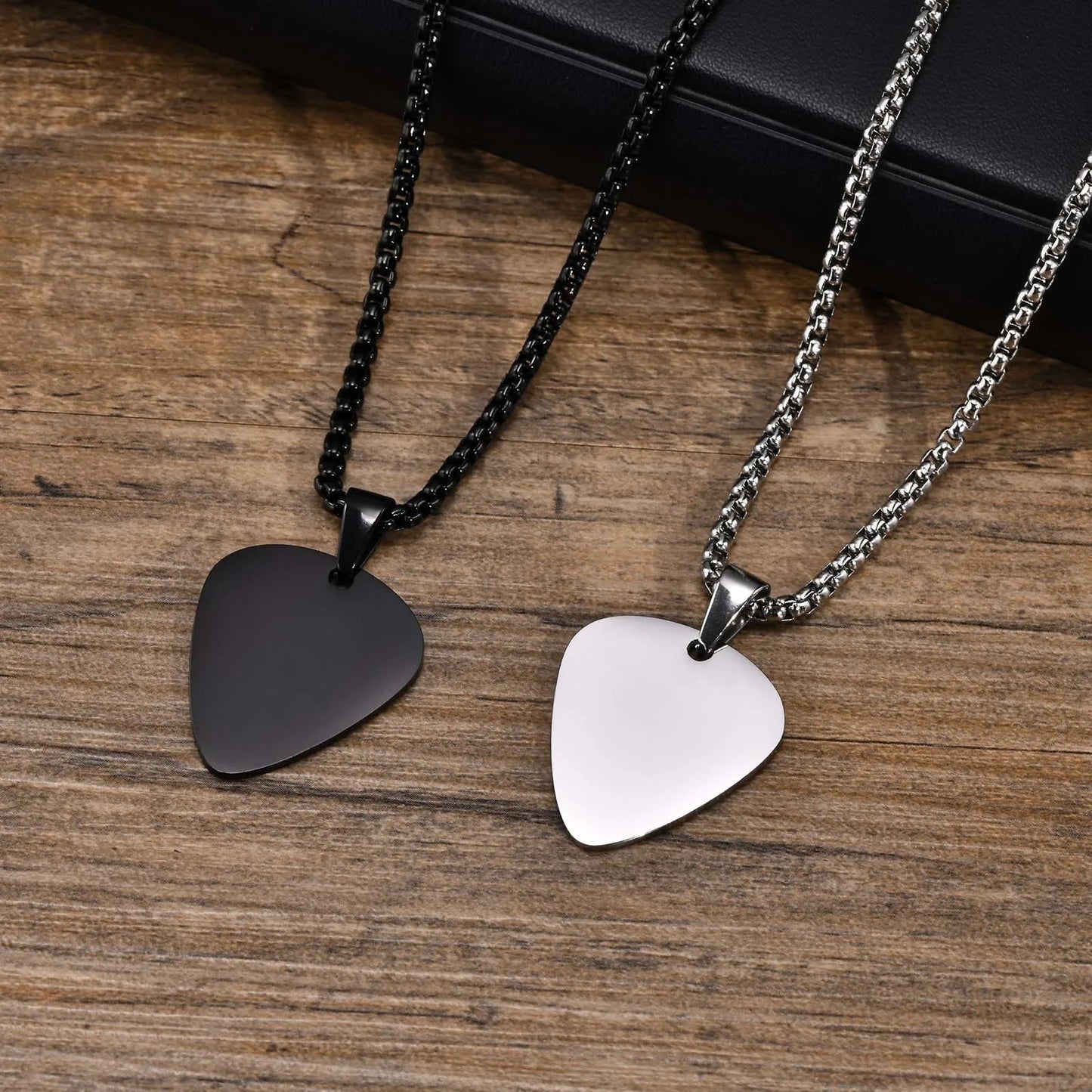Two unique stainless steel guitar pick necklaces for men with black matte and silver polished finishes and sleek chains