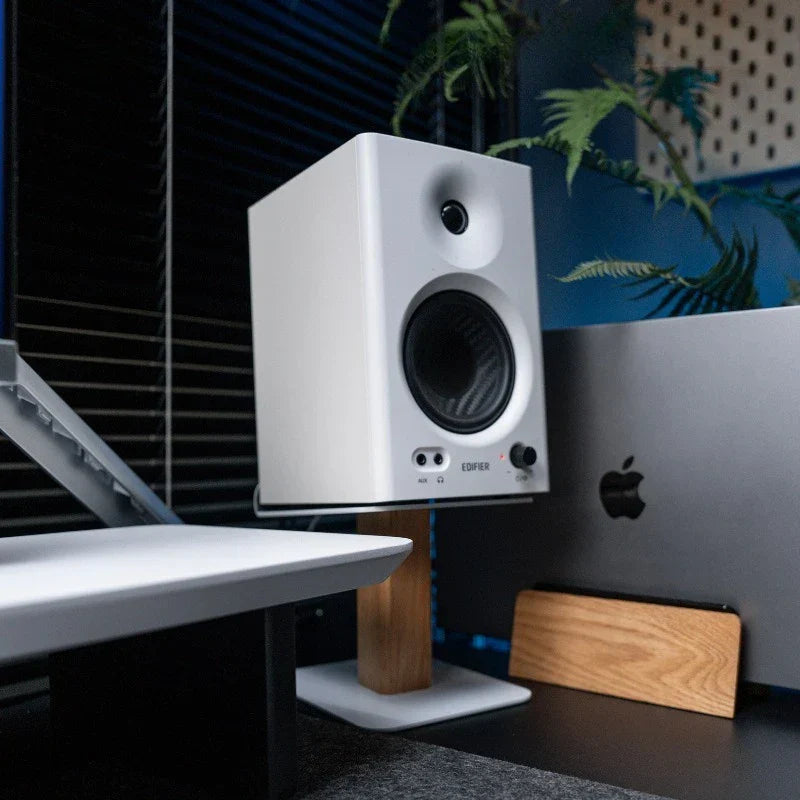 White edifier speaker with black circular drivers on a walnut oak wood speaker stand with metal base modern desk organizer