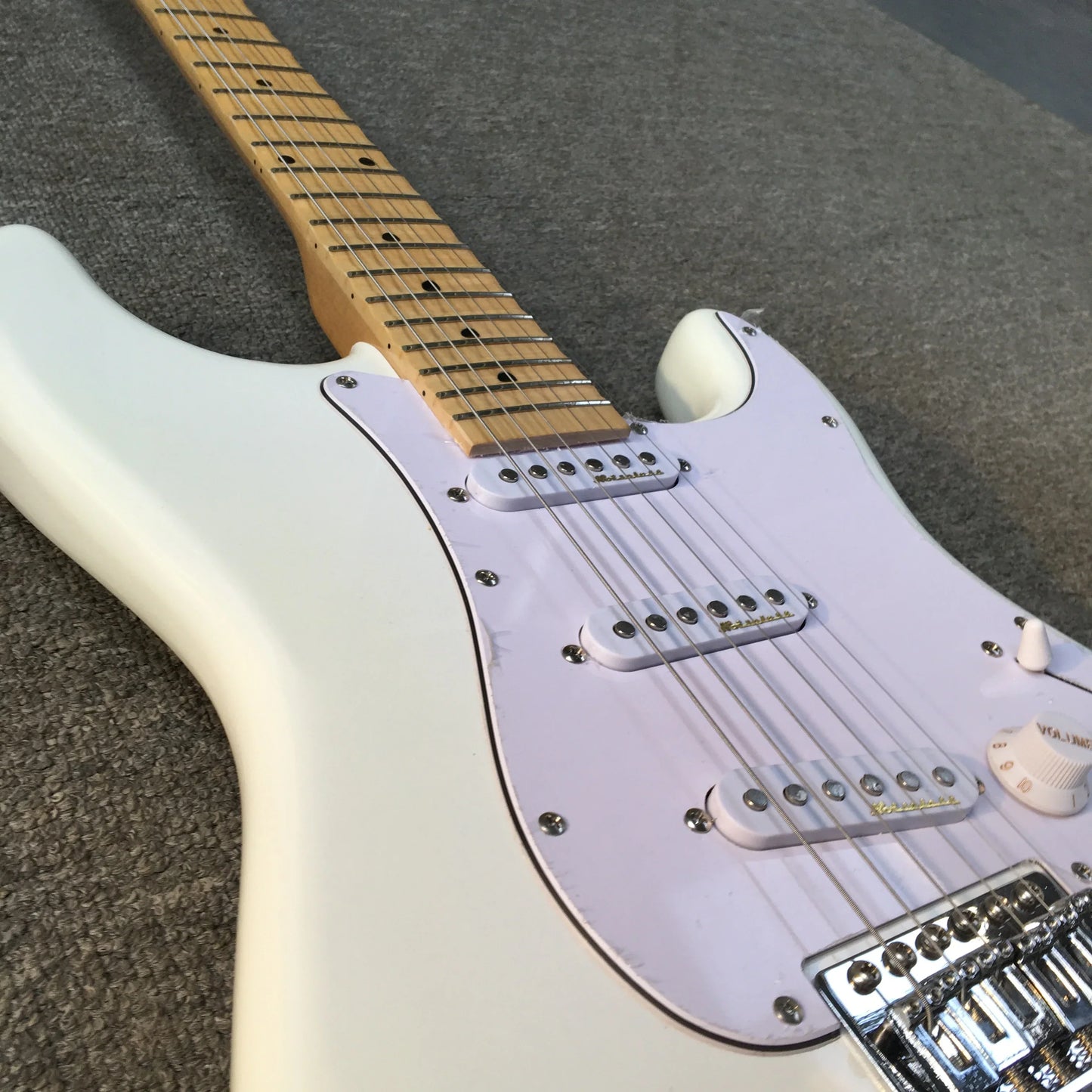 White electric guitar with maple fingerboard features glossy body sparkling sss chrome hardware and vibrato system