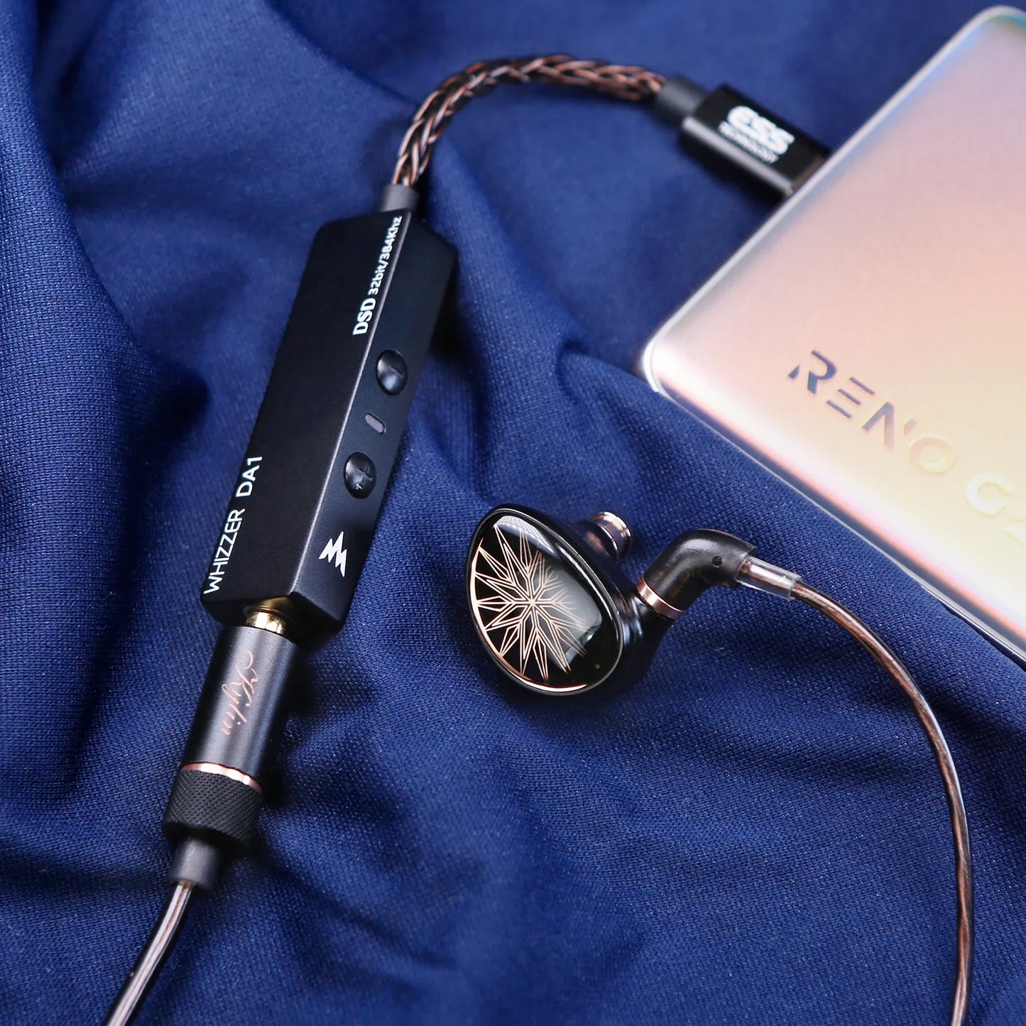 Black whizzer da1 portable usb c amplifier with gold accents and mic volume control connected to black starburst in-ear monitor