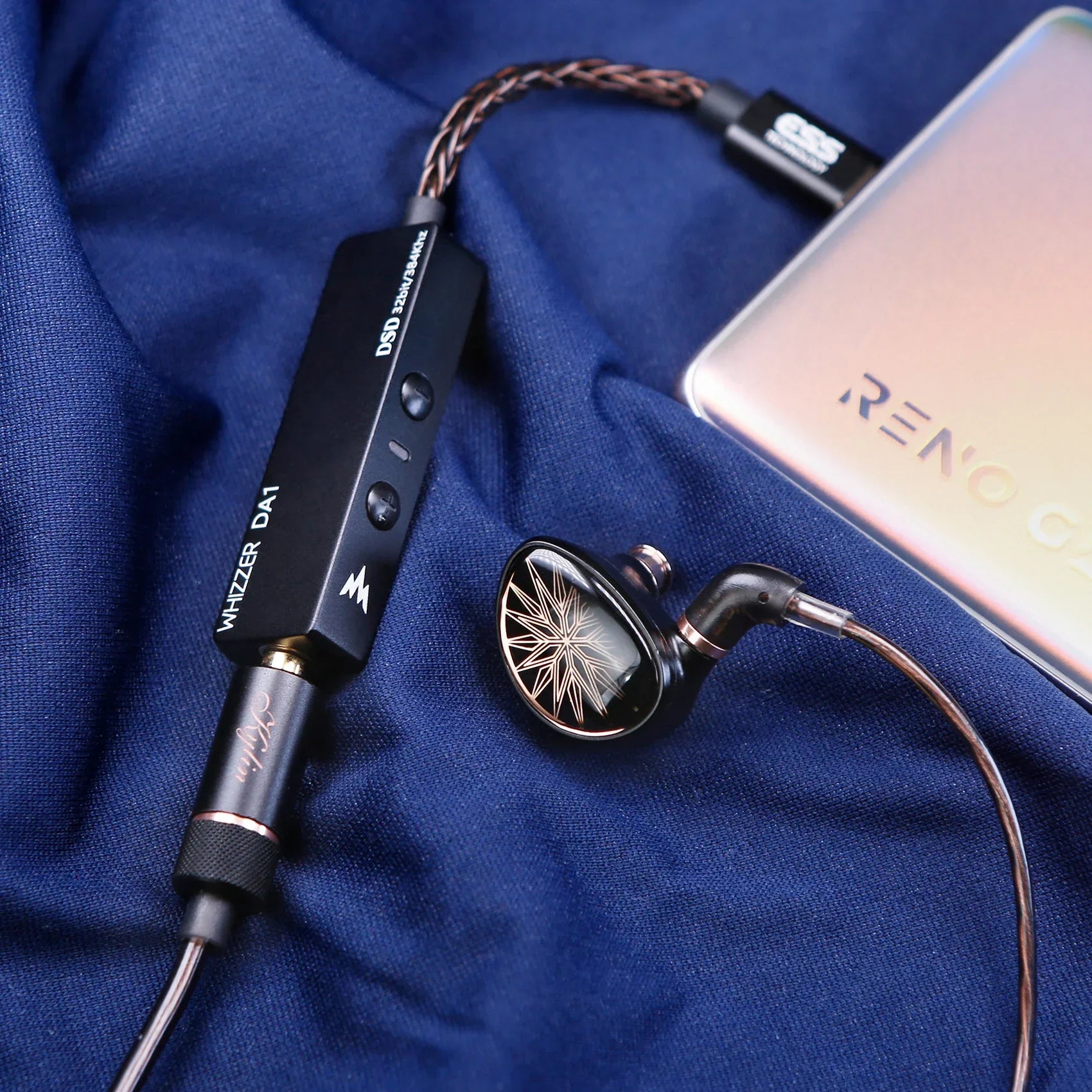 Black whizzer da1 portable usb c amplifier with gold accents and mic volume control connected to black starburst in-ear monitor