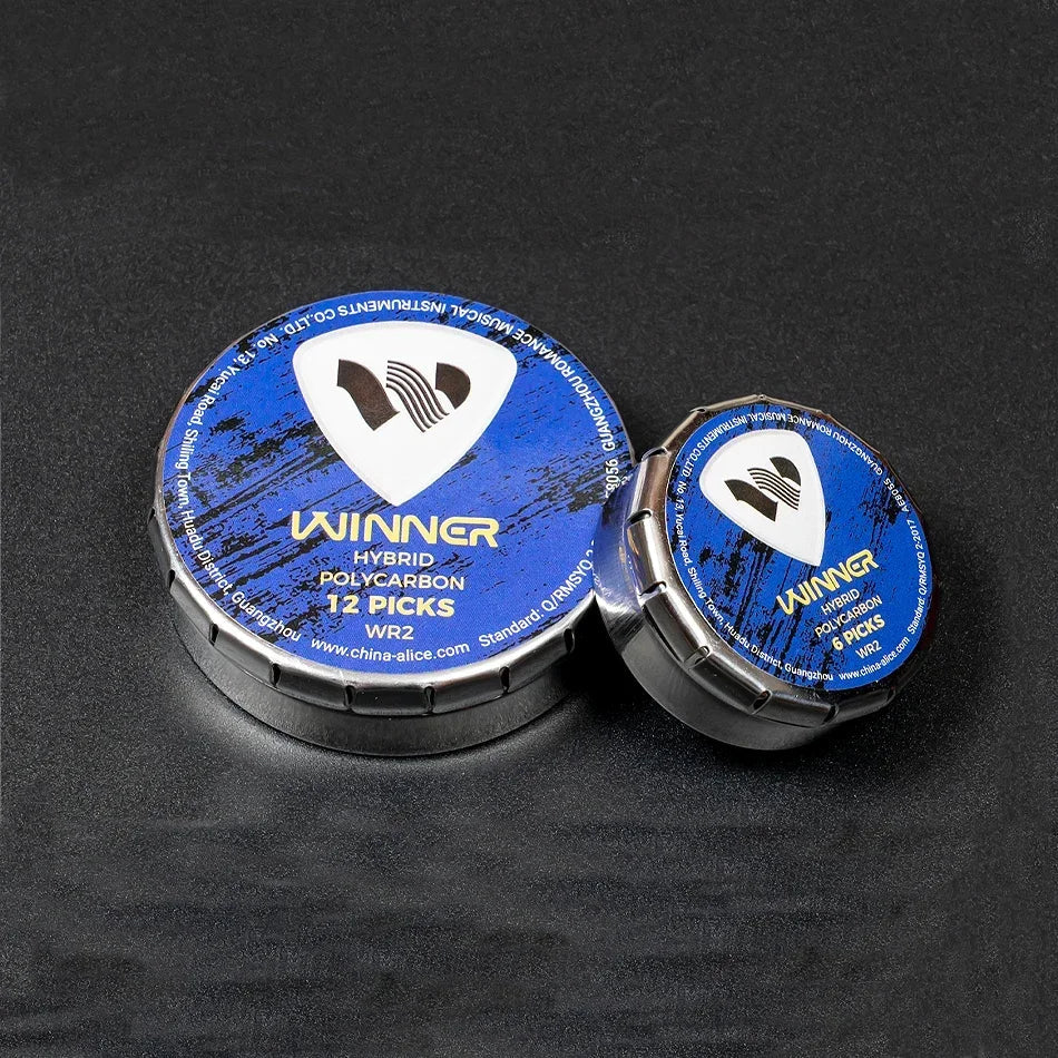 Two circular metal containers with blue lids hold winner hybrid polycarbon guitar picks for acoustic electric guitar use