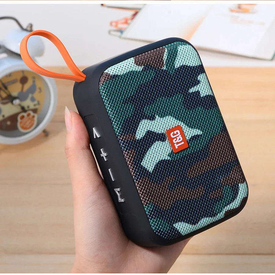 A compact camouflage wireless bluetooth speaker with mesh grille and orange loop featuring radio fm waterproof and small subwoofer sound