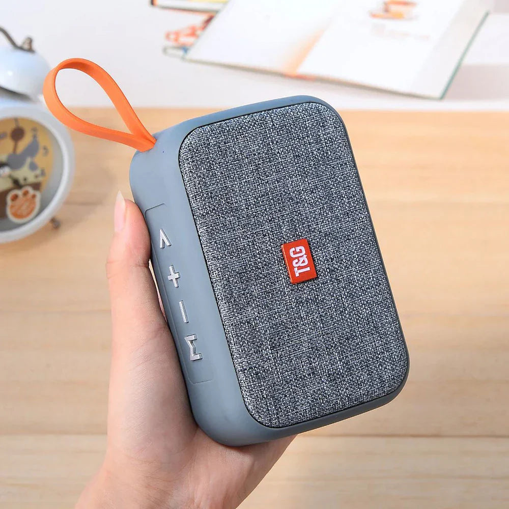 Gray textured fabric wireless bluetooth speaker with orange loop and red t&g logo radio fm waterproof small subwoofer sound