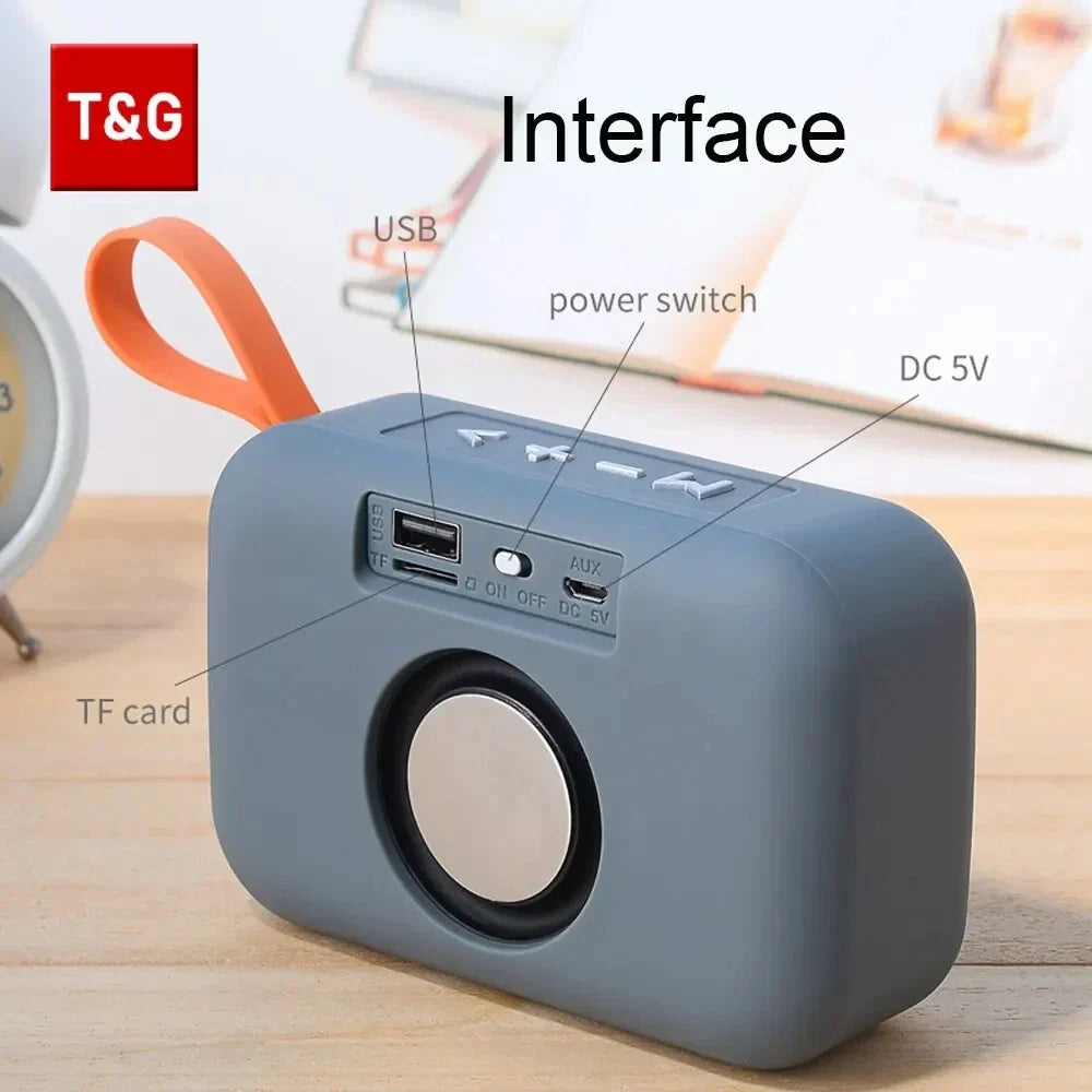 Gray wireless bluetooth speaker with orange carrying loop and circular front grille featuring small subwoofer sound and radio fm waterproof functions