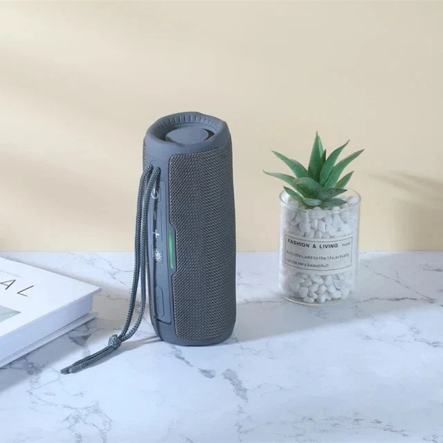 Gray cylindrical wireless portable bluetooth speaker with textured mesh exterior, carrying strap, radio fm subwoofer, audio hand free