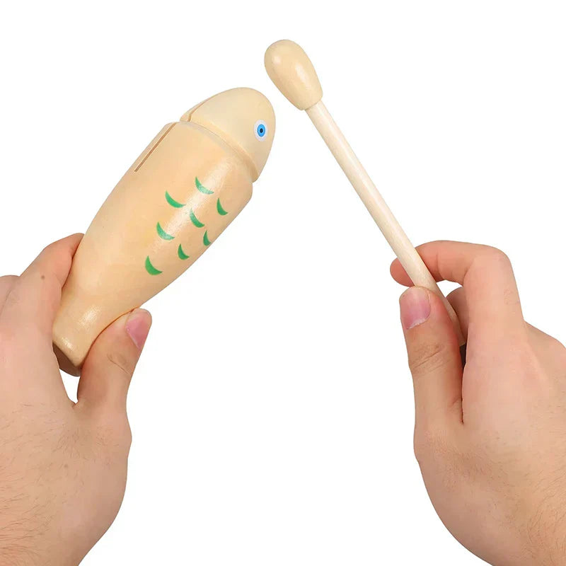 Beige wooden fish orff percussion instrument with green scales and blue eye and matching stick for beginners rhythm use