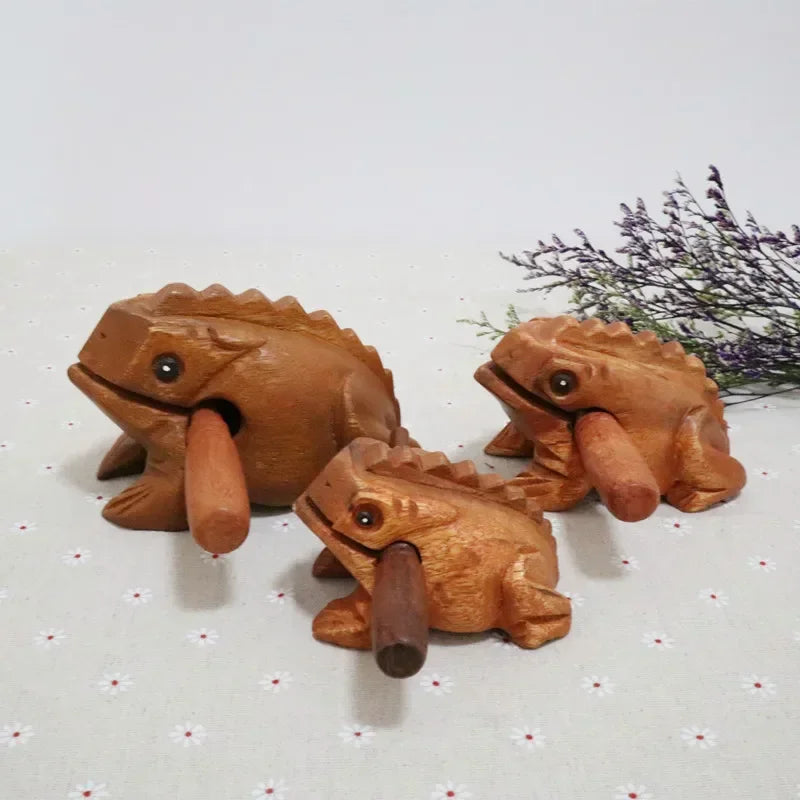 Three hand-carved wooden lucky frogs with smooth brown finish and detailed ridged backs croaking musical instruments