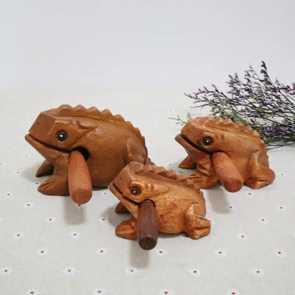 Three hand-carved wooden lucky frogs with smooth brown finish and detailed ridged backs croaking musical instruments