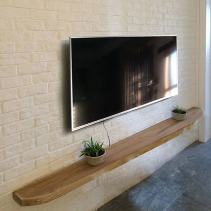 A sleek modern tv with a thin silver frame mounted on a white brick wall complements bedroom minimalist mounted stands