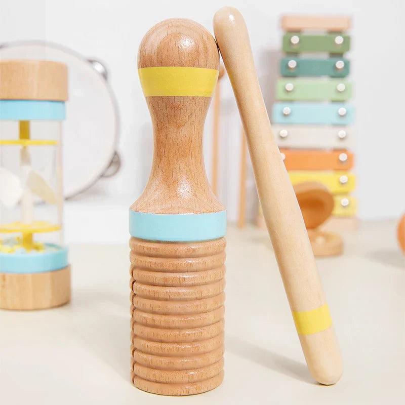 Wooden shaker with light blue and yellow bands and matching drumstick in a musical instrument montessori set for kids