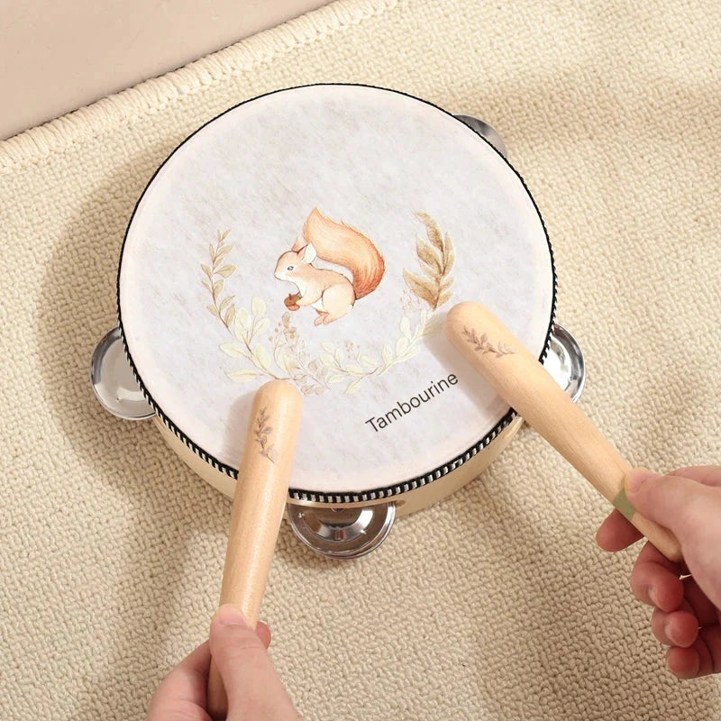 A white wooden tambourine with a squirrel illustration and silver jingles featuring wooden drumsticks for instruments baby montessori education