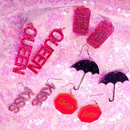 Sparkly pink and black glittery y2k earrings shaped like queen ticket stubs umbrellas and stop signs with cute flame snake and lightning queen alien designs