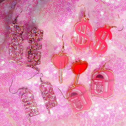 Pink glittery dollar sign y2k earrings with glossy translucent finish and gold-toned hooks from cute flame snake lightning queen alien set