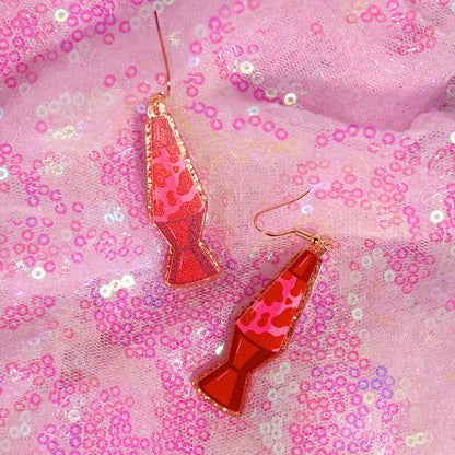 A pair of vibrant red and pink y2k earrings shaped like lava lamps with glossy resin finish and gold-toned hooks