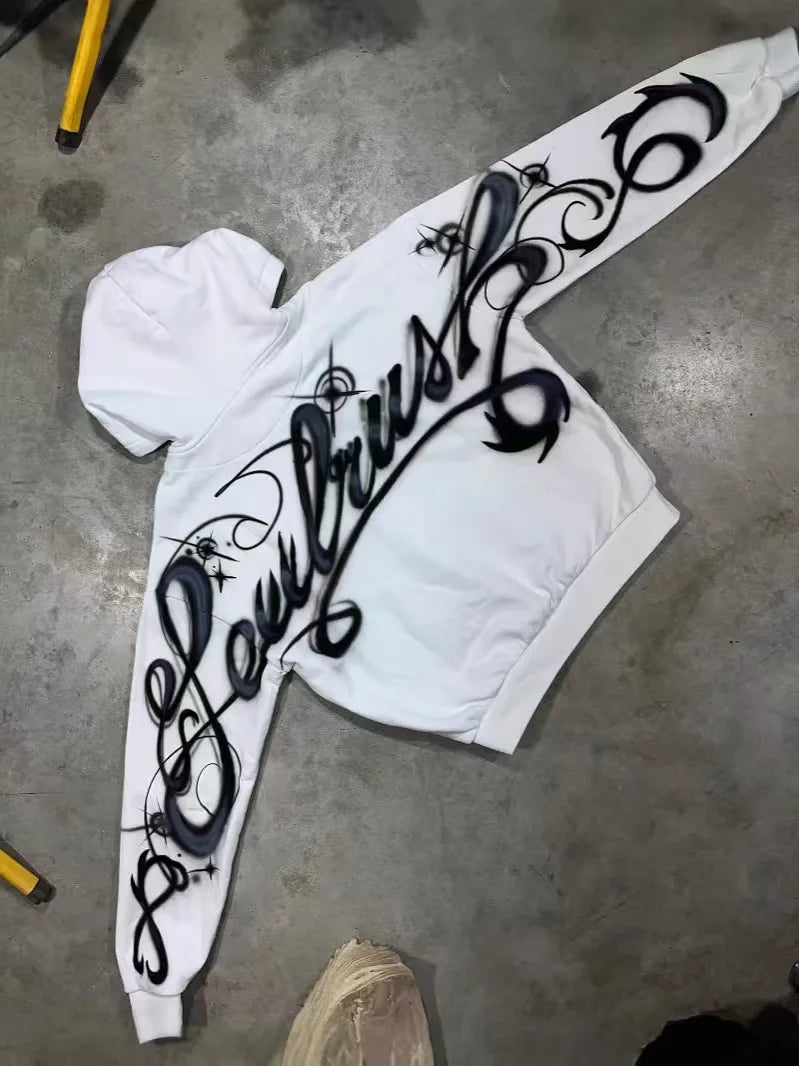 White hoodie with bold black y2k harajuku gothic graffiti lettering and decorative swirls on the back oversized zipper sweatshirt