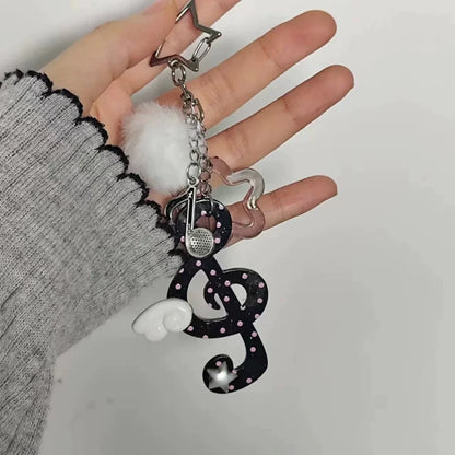 Black glittery treble clef keychain with pink polka dots white wing charm and silver microphone accent y2k harajuku musical accessory