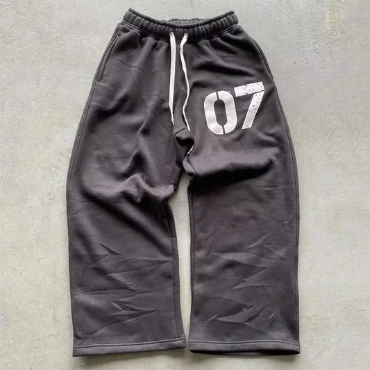 Dark gray Y2K casual baggy sweatpants with white drawstrings and distressed 07 graphic for streetwear style