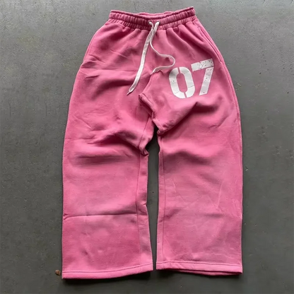 Pink baggy sweatpants with white 07 graphic and matching drawstrings part of y2k new streetwear casual set